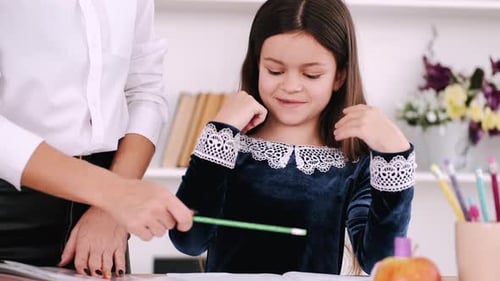 Person in White Shirt Explaining Exercise To Schoolgirl in Library