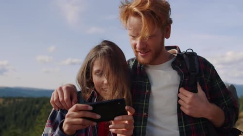 Couple Looking at Smartphone on Mountain Top
