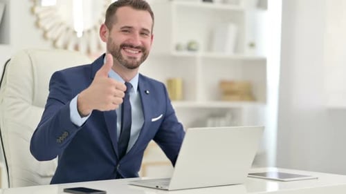 Happy Businessman Gives Thumbs Up at Desk