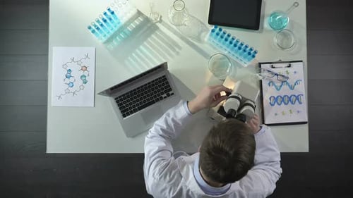Scientist Working with Microscope and Laptop in Lab
