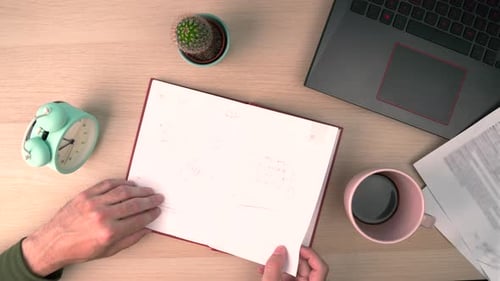 Top View of Work Desk Hand Tearing Page From Notebook