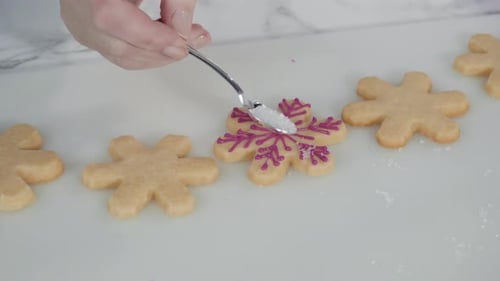 Step by step. Icing snowflake shaped sugar cookies with pink royal icing.
