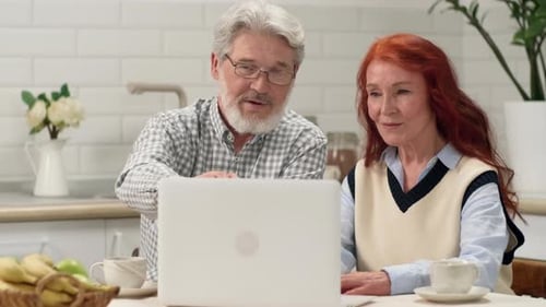 Senior Couple Video Chatting on Laptop in Kitchen