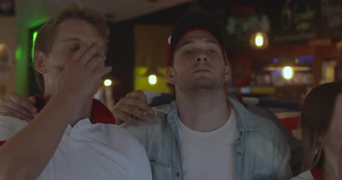 British football fans reacting to defeat while watching match in sports bar, slow motion