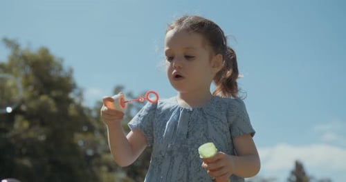 Cute Girl Blowing Bubbles in the Park