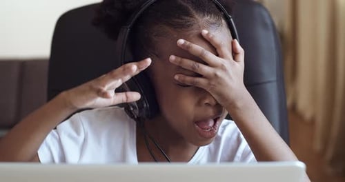 Child With Laptop Wearing Headphones At Home