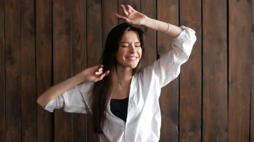 Woman Dancing Happily in Front of Wooden Wall