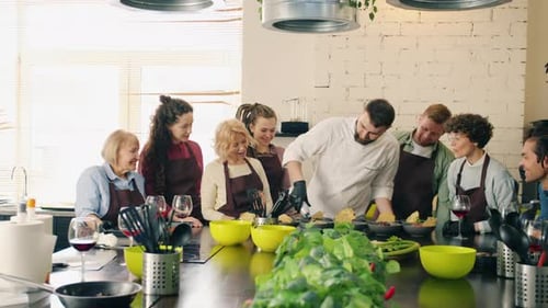 Professional Chef Teaching Group of Students Making Meals and Talking in Kitchen