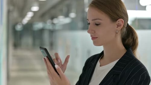 Young Woman Uses Phone in Modern Office