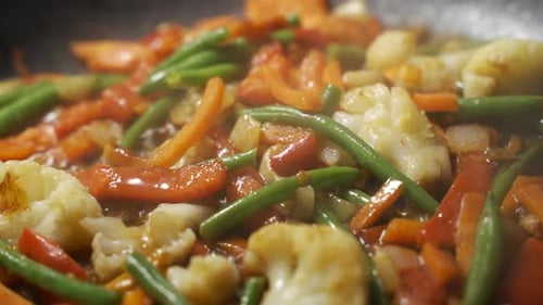Nahaufnahme Koch beim Kochen von Gemüse in der Pfanne
