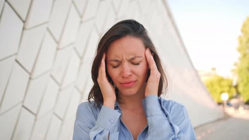 Woman Massaging Temples Suffering from Headache Outdoors