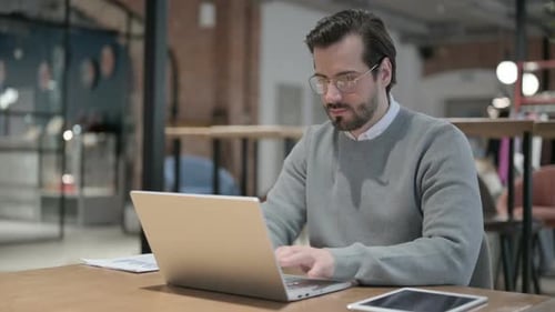 Young Man Working on Laptop in Office