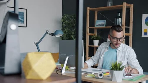 Zeitlupenporträt eines Smartphone-App-Designers, der mit dem Gerät schreibt und mit dem Computer tippt