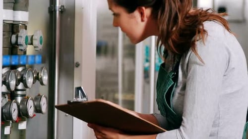 Travailleur tenant un dossier sur un bloc-notes en usine