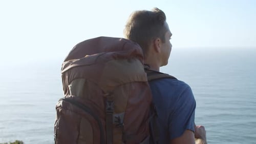 Happy Male Backpacker Standing at Rocky Cliff