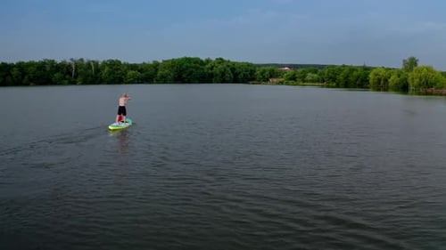 Drone shot of young man stand up paddling on vacation