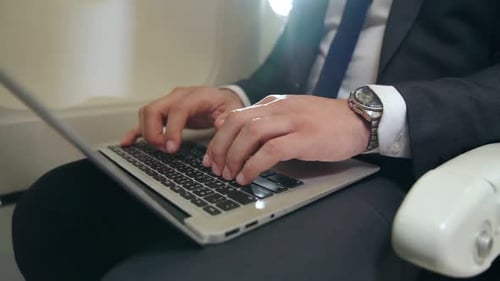 Man in Suit Typing on Laptop in Flight