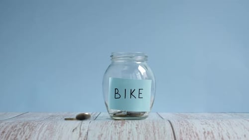 Coins Dropping into Savings Jar for Bike