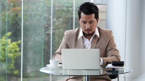 Focused Man Typing on Laptop with Coffee