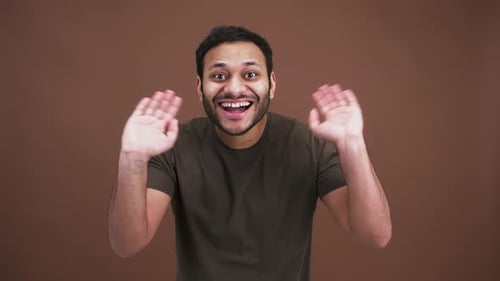 Studioporträt eines fröhlichen, freundlichen Arabers, der mit den Händen vor die Kamera winkt und Hallo sagt