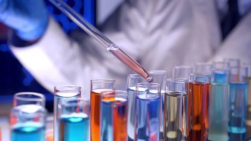 Scientist Adds Liquid to Test Tubes in Lab