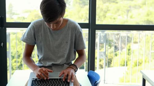 Teenage Boy Working on Laptop Indoors