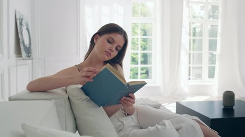 Woman Reading a Book on Couch at Home