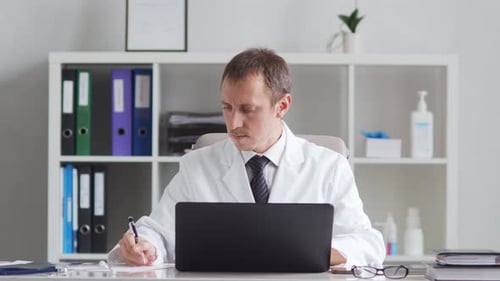 Professional medical doctor working in hospital office using computer technology.