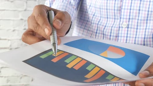 Man Hand with Pen Analyzing Bar Chart on Paper