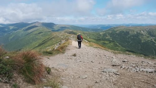 Tourist with a Backpack Goes Down Along the Stone Mountain Trail on the Hill
