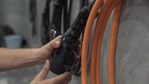 Electric Charger in Hand at Charging Station