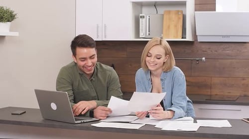 Happy Couple Reviews Finances at Kitchen Counter