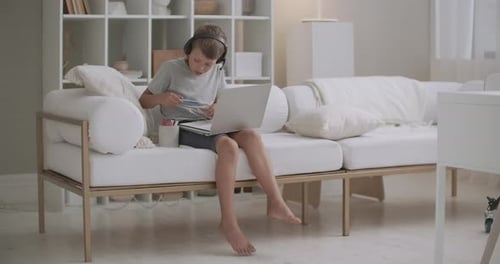 Boy Studies with Laptop and Headphones at Home