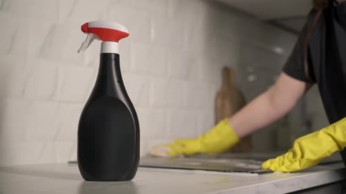 Woman cleaning the stovetop with yellow gloves