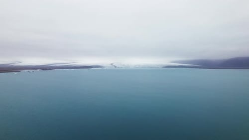 Blue Ocean With the View of the Snowy Mountains Under the Clear Skies