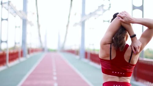 Woman Stretching Triceps on Pedestrian Bridge