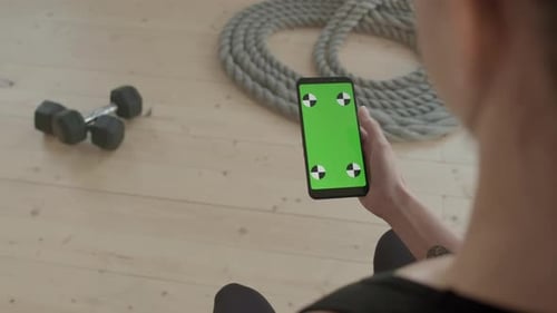 Person Using Green Screen Smartphone in Home Gym