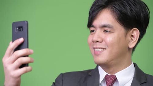 Young Adult Businessman Uses Smartphone and Smiles