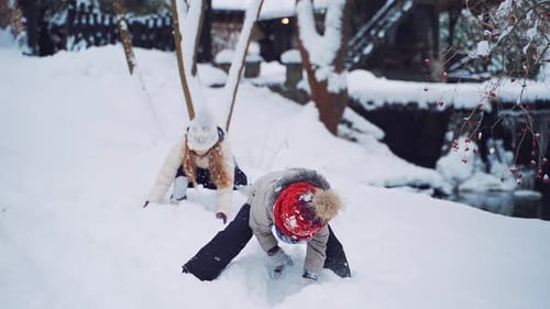 Fröhliche Kinder werfen weichen Schnee auf den Hintergrund des Winterflusses.