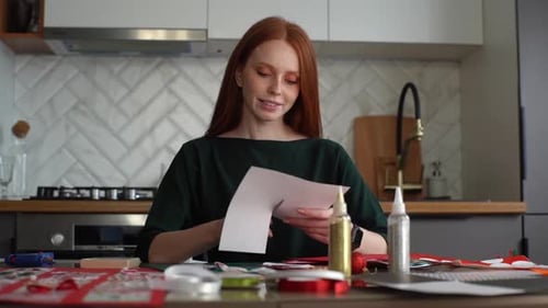 Woman Cutting Paper at Kitchen Table Crafting