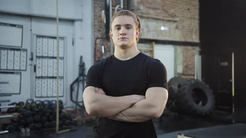 A Strong Athlete is Crossing His Arms and Looking at the Camera