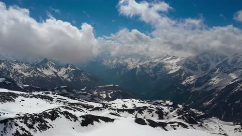 Air Flight Through Mountain Clouds Over Beautiful Snowcapped Peaks of Mountains and Glaciers