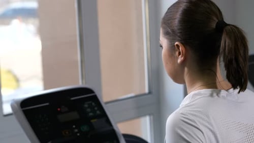A Girl Runs on a Treadmill in a Sports Club