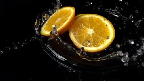 Orange Slices Dropping Into Water on Black Background
