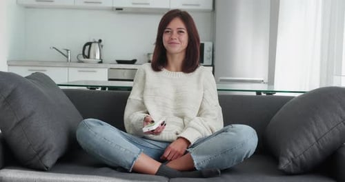 Woman Smiling on Couch with Remote