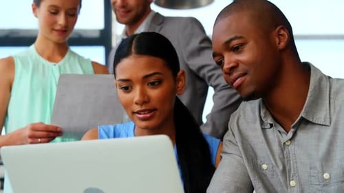 Diverse Team Collaborating on Laptop in Modern Office