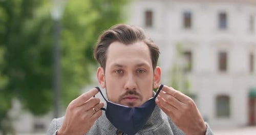 Young Adult Puts On a Blue Face Mask