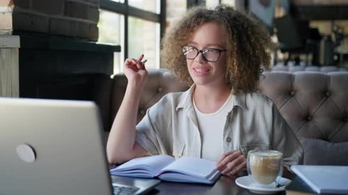 Girl Learn Remote Training Via Video Communication Sitting at Table in Restaurant