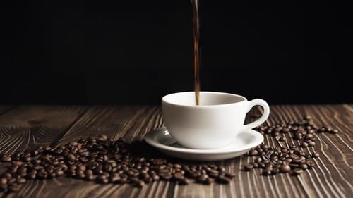 Fresh Coffee Poured into White Cup with Coffee Beans