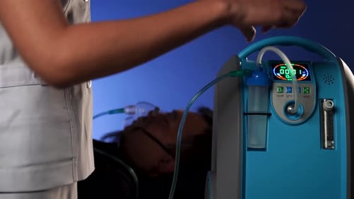 Il porte un masque à oxygène en raison de difficultés respiratoires et une infirmière pour l'aider à s'occuper de